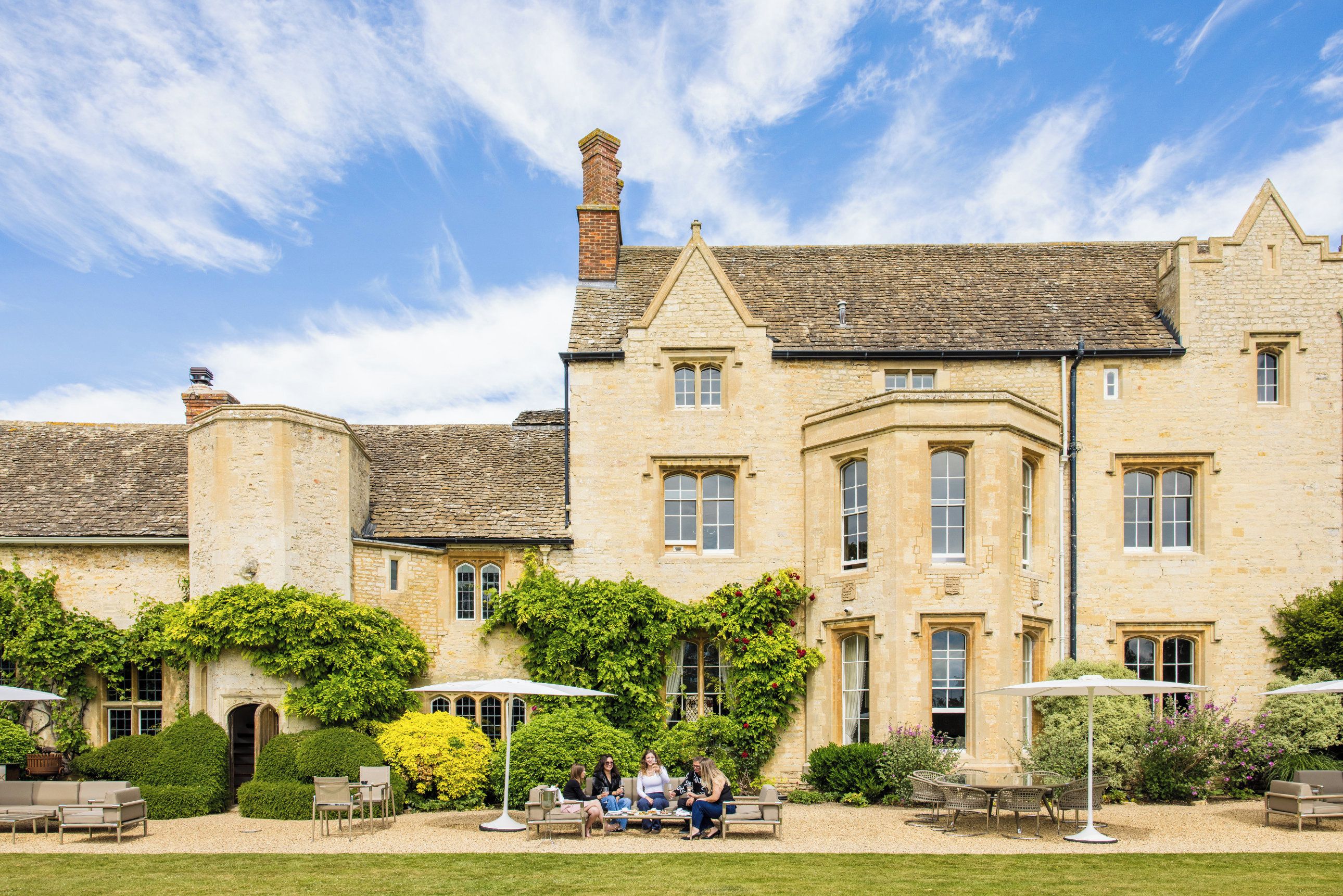 A historic stone building with a courtyard, outdoor seating, and a well-maintained garden.