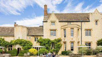 A historic stone building with a courtyard, outdoor seating, and a well-maintained garden.