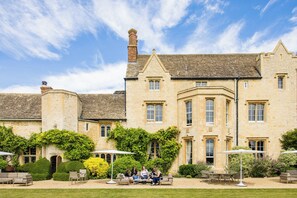 A historic stone building with a courtyard, outdoor seating, and a well-maintained garden. - Weston Manor (Bicester)