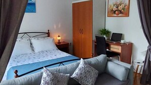 A bedroom with a bed, a sofa, a desk with a computer, a wardrobe, and a painting on the wall. - Green Garden Oasis (Opatija)