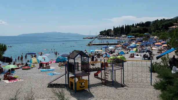A beach with a playground, umbrellas, and a clear view of the sea. - Green Garden Oasis (Opatija)