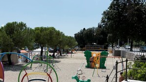 A playground with various play equipment including swings, slides, and climbing structures. - Green Garden Oasis (Opatija)