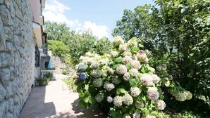 A stone building with a garden path leading to a lush hydrangea bush. - Green Garden Oasis (Opatija)