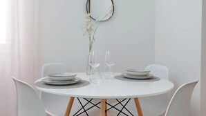 Taula rodona blanca amb dos plats, dues copes i un ram de flors seques.