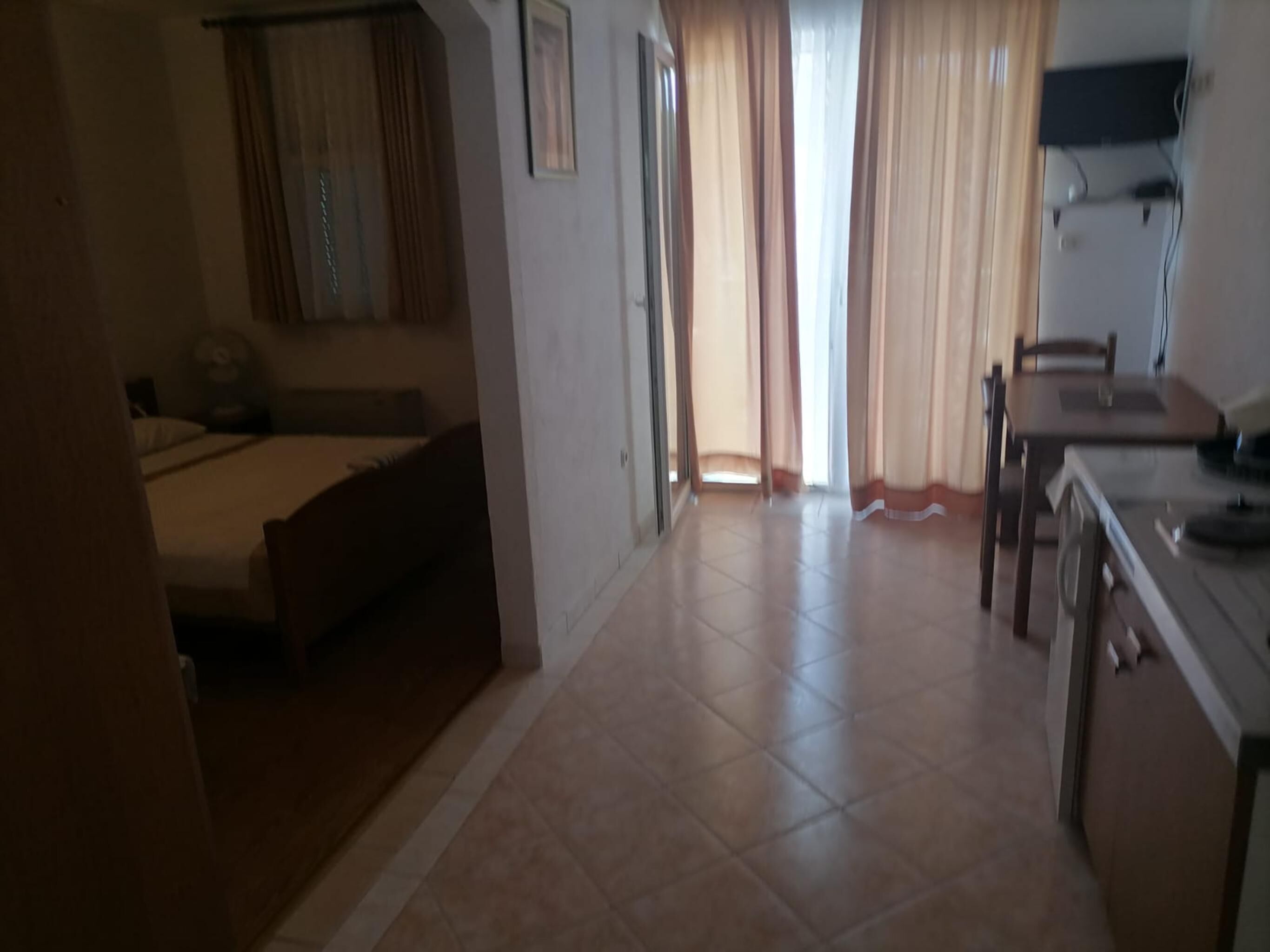A hotel room with a bed, a desk, and a chair. There is a window with curtains.