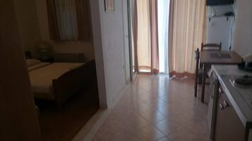 A hotel room with a bed, a desk, and a chair. There is a window with curtains.