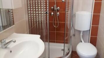 Un baño con cabina de ducha, lavabo e inodoro.