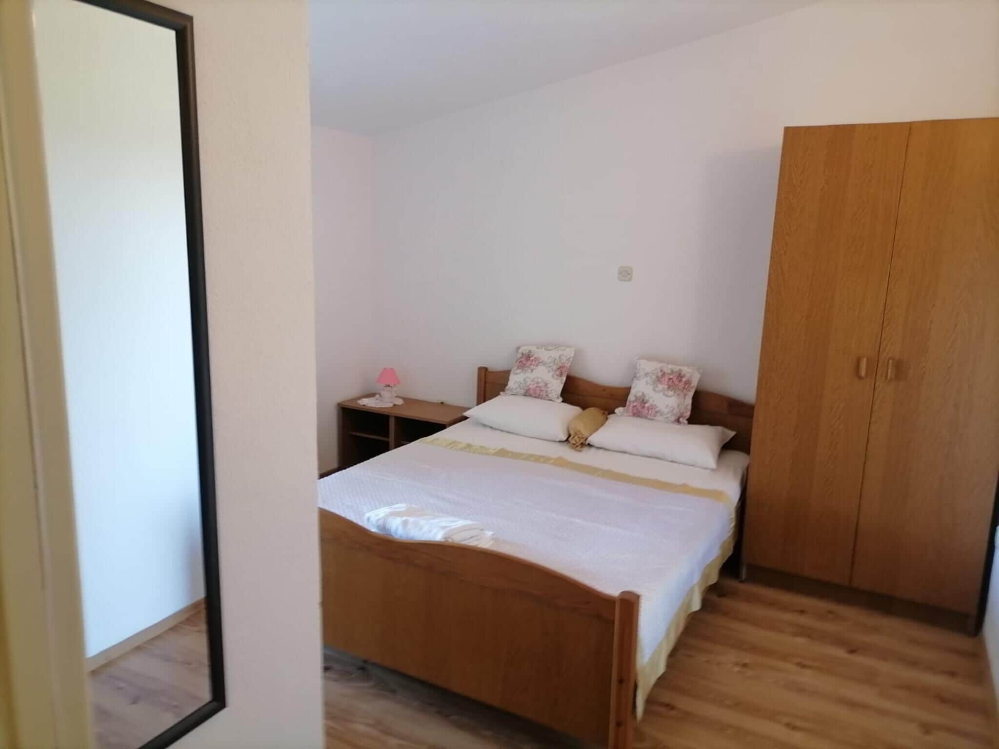 Ein Schlafzimmer mit einem hölzernen Bett, einem Nachttisch, einem Kleiderschrank und einem kleinen Tisch mit Lampe.