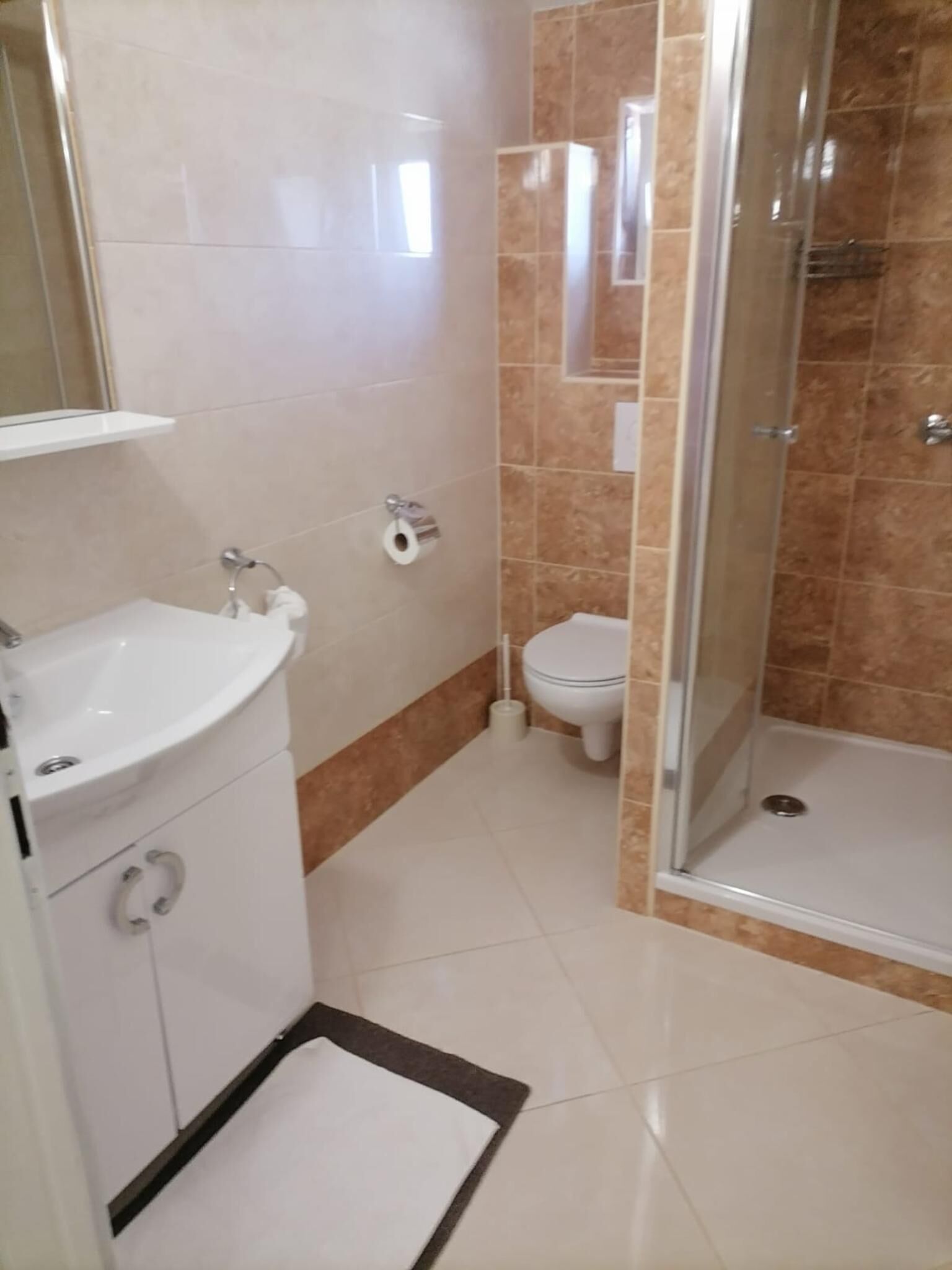 Casa de banho com lavatório branco, sanita e chuveiro.