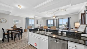 Una cocina moderna con encimera de granito negro, armarios blancos y electrodomésticos de acero inoxidable.