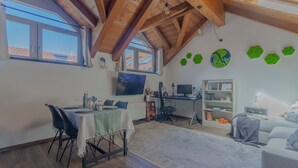 A spacious room with a dining area, a desk, and a sofa.