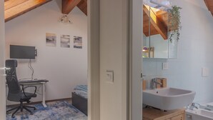 A modern bedroom with a desk, chair, and artwork on the wall.