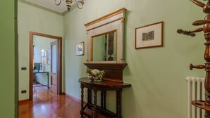 A hallway with wooden flooring, a wooden console table with a mirror, and a radiator. - Daisy Home by Varenna Holidays (Varenna)