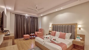 Una habitación de hotel moderna con una cama grande, un escritorio, una silla, un televisor y un ventilador de techo.