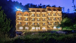 Un hotel de varios pisos con balcones, un letrero que indica que es el Hotel Tejas y vistas del entorno.