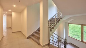 Un pasillo amplio y luminoso con una escalera moderna y un ventanal que ofrece vistas al exterior.