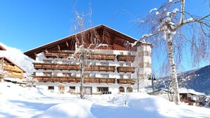 Ein mehrstöckiges Hotel mit hölzernen Balkonen, umgeben von verschneiter Landschaft und Bergen.