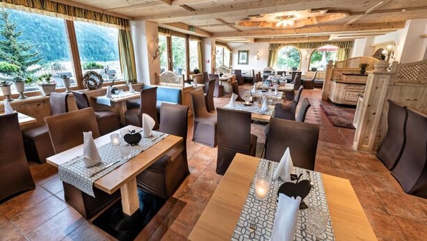 Ein Restaurant mit Holzeinrichtung, mehreren Tischen und Stühlen.