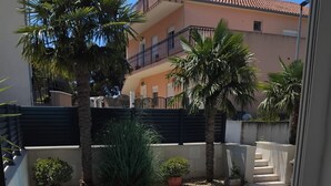 A residential building with a balcony, palm trees, and a gated entrance. - Villa Marija (Podstrana)