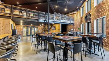 Un restaurant spacieux doté de nombreuses tables et chaises, d’une mezzanine aménagée en espace détente et d’un mur intérieur en briques.