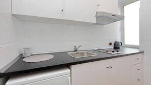 Cocina moderna con armarios blancos, dos fregaderos, encimera negra y ventana que proporciona luz natural.