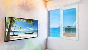 Een badkamer met een groot raam, een bevestigde televisie en een witte wastafel.