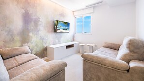 Een moderne woonkamer met een groot schilderij, een witte tv-meubel en twee ronde bijzettafels.