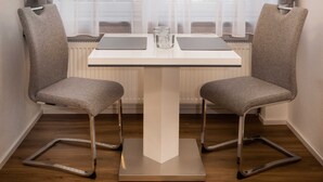 A modern dining area with a white table, two grey chairs, and a pendant light. - Bergromantik Oberstdorf - Tiefenbach (Oberstdorf)