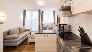 A compact living space with a kitchenette, a sofa, a dining table, and a TV. - Bergromantik Oberstdorf - Tiefenbach (Oberstdorf)