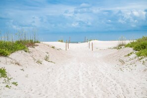 A sandy beach path leading to the sea with wooden posts and sparse vegetation. - Buddha's Surf Shack (St. Augustine)