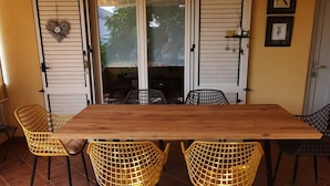 A dining area with a wooden table and yellow chairs, a sliding glass door, and a view of the outdoors. - Apartment Stella Casa Bruno (Vrsi)