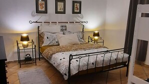 A bedroom with a metal bed frame, two bedside tables with lamps, a rug on the floor, and three framed pictures on the wall. - Apartment Stella Casa Bruno (Vrsi)