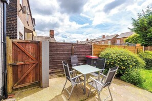 A patio with a table and chairs, a wooden gate, and a brick wall. - NEW! Spacious Home, Ideal for Groups, FREE Parking (Manchester)
