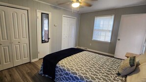 Een slaapkamer met een bed, een plafondventilator en een raam.