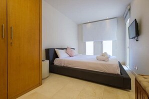 Cozy retreat with a single bed, bedside table, and wall-mounted TV.