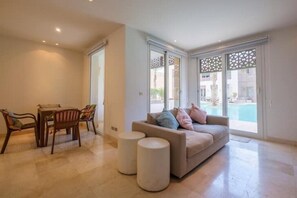 Relax in a space with a sofa, dining table, and access to an outdoor pool.