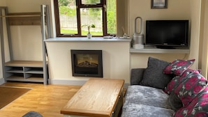 Ein Wohnzimmer mit Sofa, Couchtisch, Fernseher und Kamin.