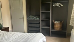 Ein Schlafzimmer mit einem Bett, einem grauen Kleiderschrank und einer Kleiderstange.