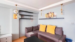 Una sala de estar con un sofá, una mesa de centro, una estantería y un reloj de pared.