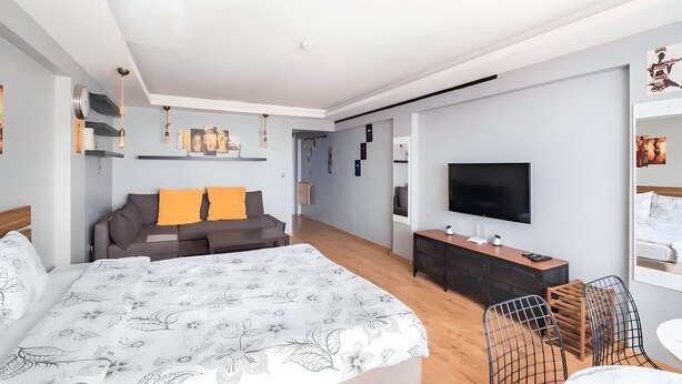 Una habitación de hotel moderna con una cama grande, un sofá, un televisor y un escritorio.