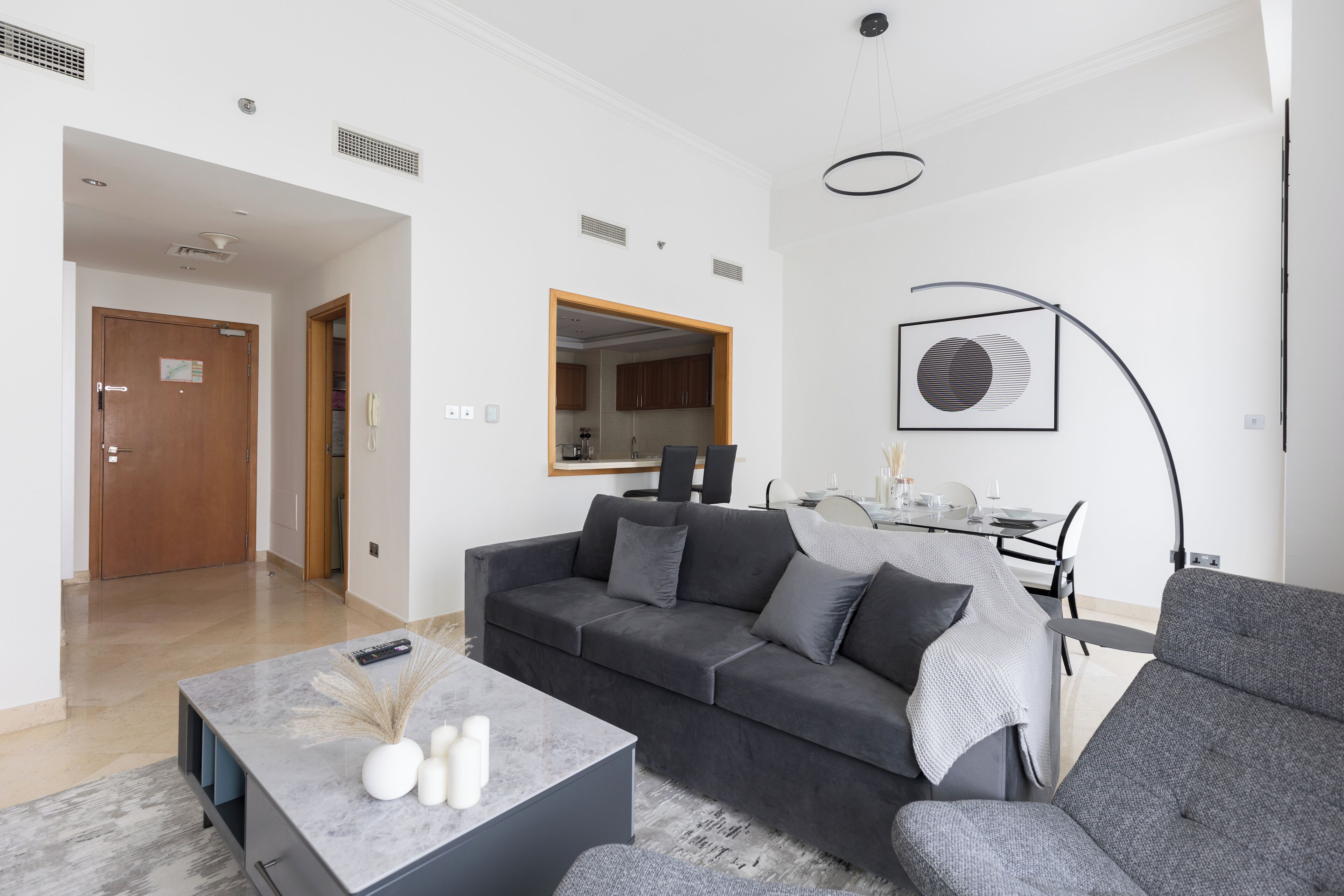 Una sala de estar moderna con un sofá gris, una mesa de centro y un comedor con mesa y sillas.