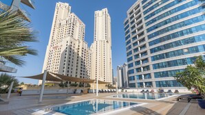 A pool area with lounge chairs and a canopy, surrounded by high-rise buildings.