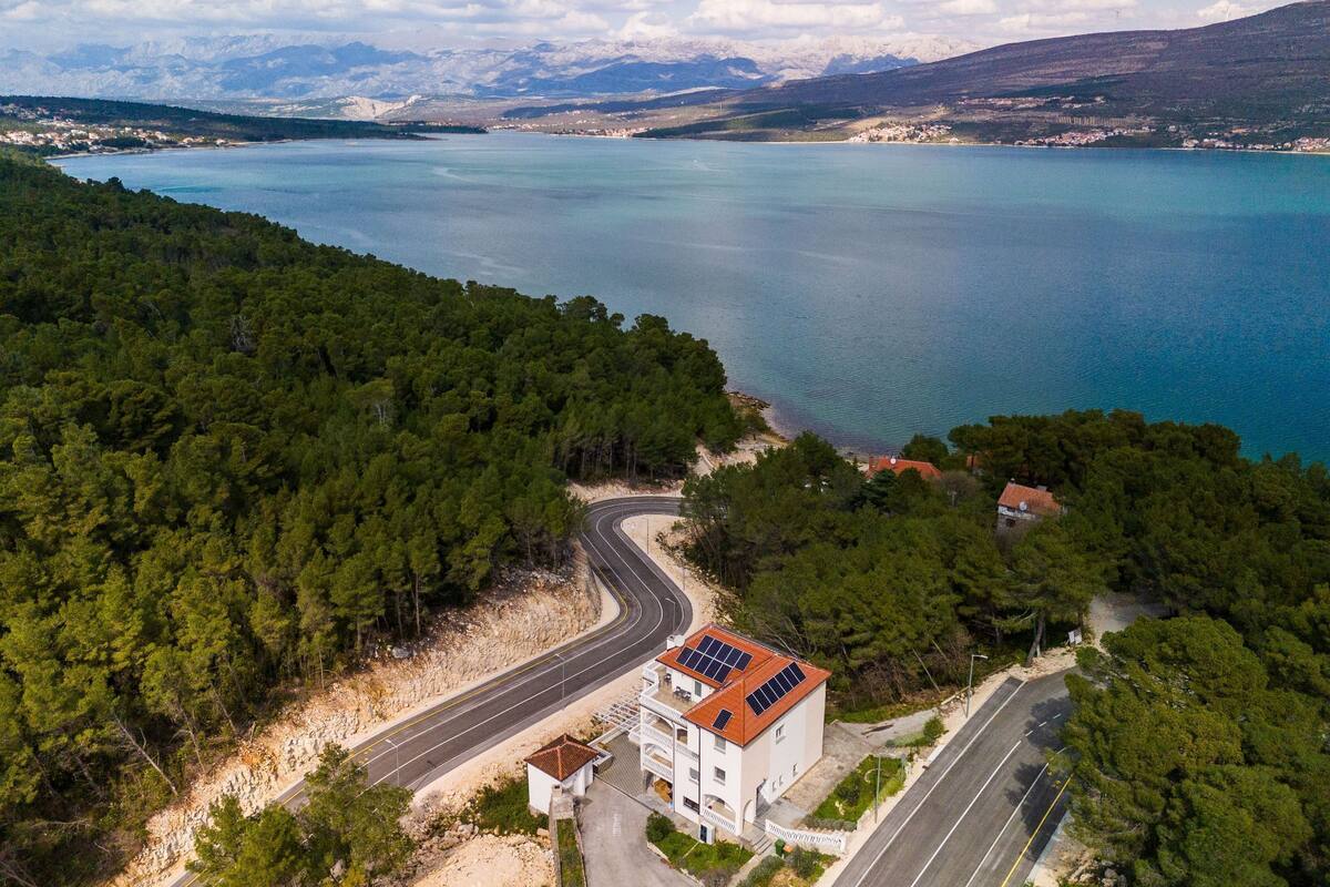 Una carretera costera serpentea por una zona boscosa con un edificio que cuenta con paneles solares.
