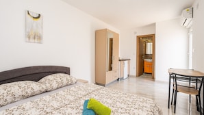 Un dormitorio con cama, escritorio y baño a la vista a través de una puerta abierta.