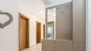 Un pasillo con puertas de madera, un espejo grande y un armario beige con cajones.