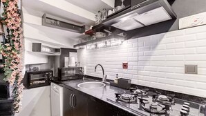 Eine moderne Küche mit schwarzem Arbeitsplatz, weiß gefliestem Fliesenspiegel und Edelstahlgeräten.