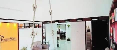 Un espacio habitable amplio con diseño moderno, que incluye un sofá grande, una mesa de centro y una silla colgante.