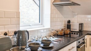 A modern kitchen with white subway tiles, a window with blinds, a stainless steel range hood, and a microwave.