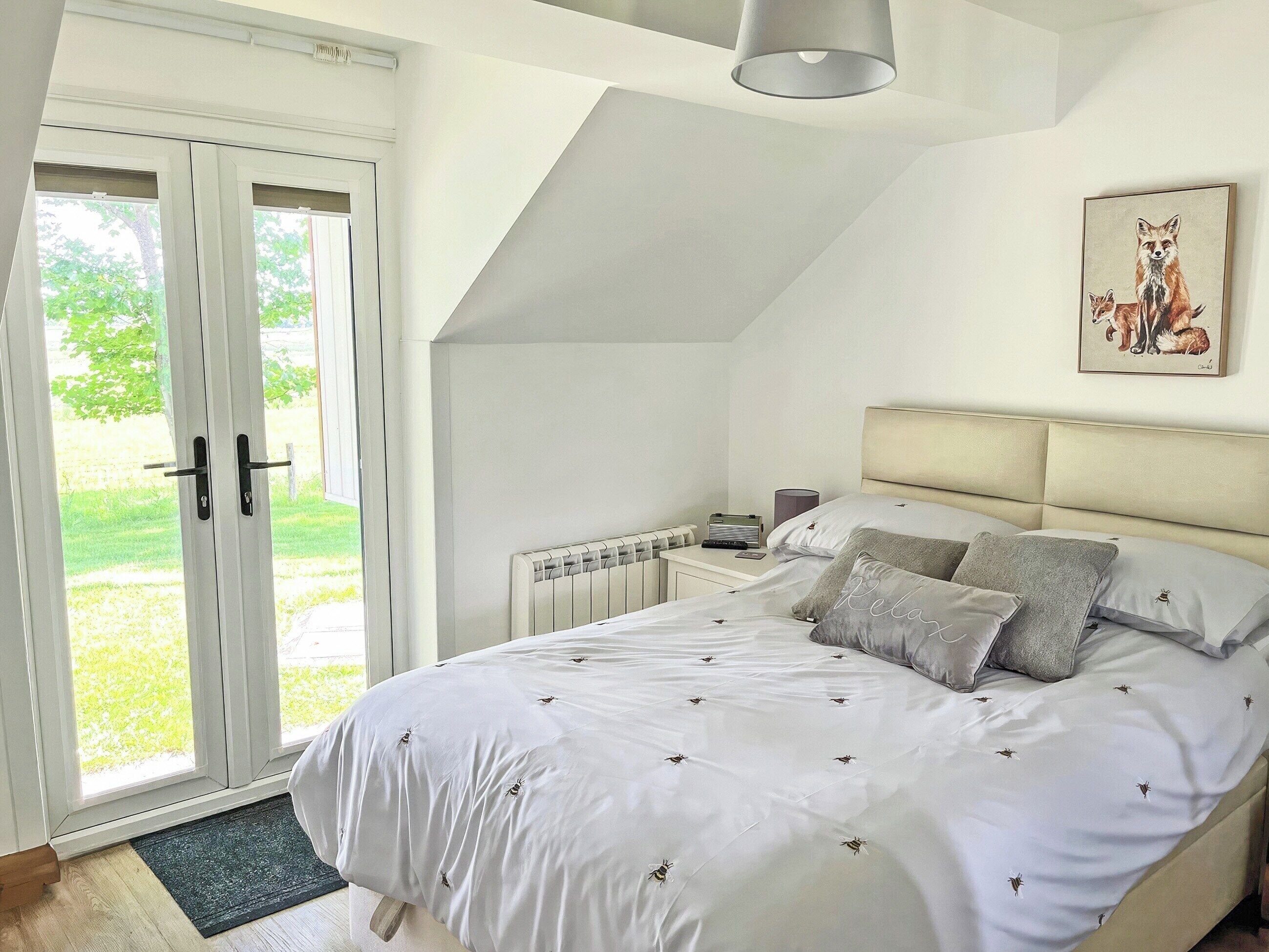 A bedroom with a large bed, a radiator, a bedside table, and a door leading to a balcony.
