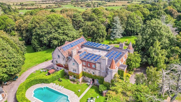 A large estate with a swimming pool, solar panels, and a well-maintained garden.